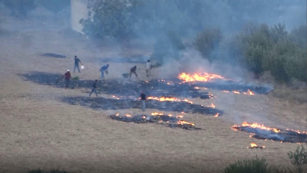 Conforme caen las llamas de los cohetes incendiarios, nubes de humo cubren las tierras de cultivo en el oeste de Idlib, Siria, el 30 de julio de 2018.