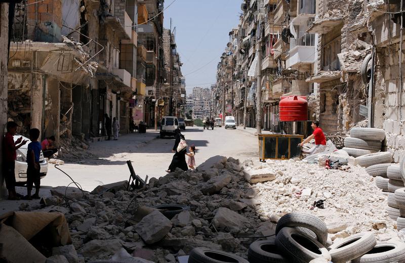A woman walks with a child amid rubble at Bustan al-Qasr neighbourhood in Aleppo, Syria July 16, 2017.