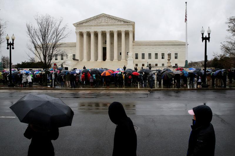 Protesters for and against abortion rights huddle under umbrellas as they rally in groups outside while the U.S. Supreme Court hears oral arguments in the abortion case National Institute of Family and Life Advocates (NIFLA) v. Becerra, in Washington, U.S