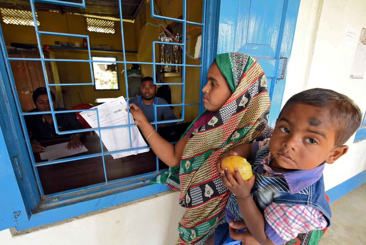 A woman carrying her son arrives to check her name on the draft list of the National Register of Citizens in Assam, India, January 2, 2018.