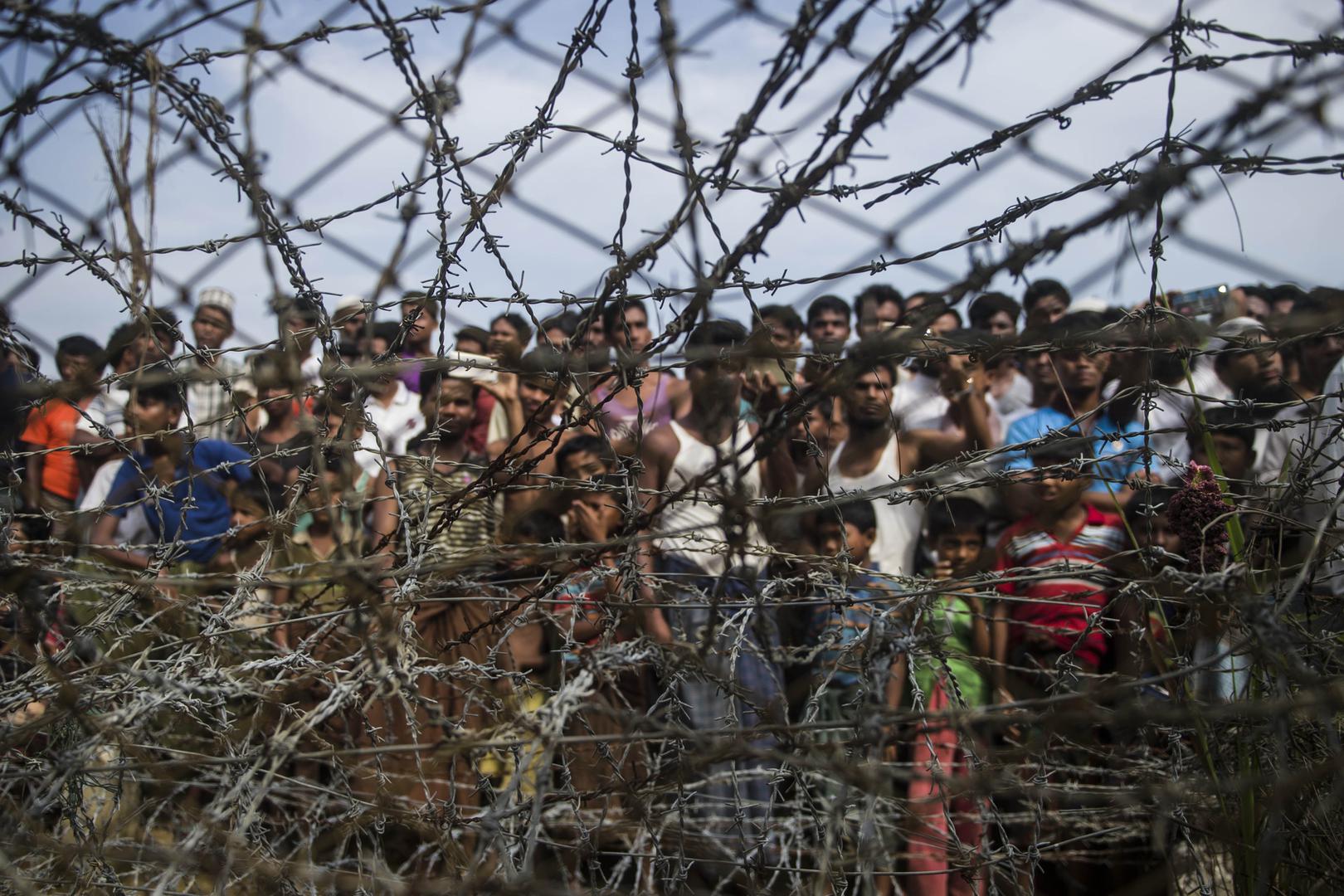 Pengungsi Myanmar berkumpul di balik pagar kawat di zona perbatasan “no-man’s land” antara Myanmar dan Bangladesh, 25 April 2015. 