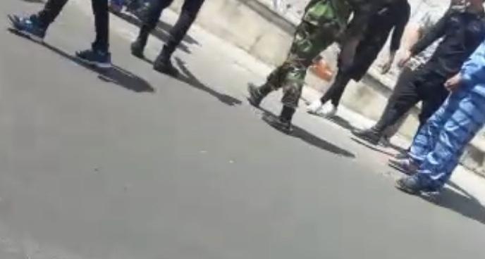تصویر از یک ویدیو که معترضین بازاشت شده را با دست بند در مقابل زندان اوین نشان میدهد، ۲۶ اگوست ۲۰۱۸.