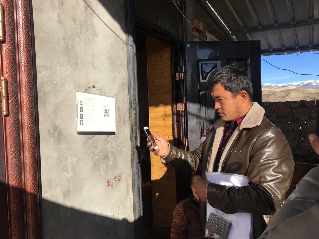 A government official scans the QR code on the wall of a home in Xinjiang, which gives him instant access to the residents’ personal information. 