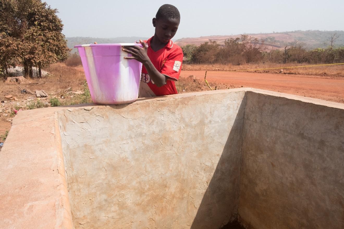 A boy fetches water from a tank used to store water delivered to Lansanayah village, in the Boké region, by tankers of Société Minière de Boké’s (SMB) consortium. Villagers say that SMB’s arrival damaged local natural water sources, forcing them to rely o