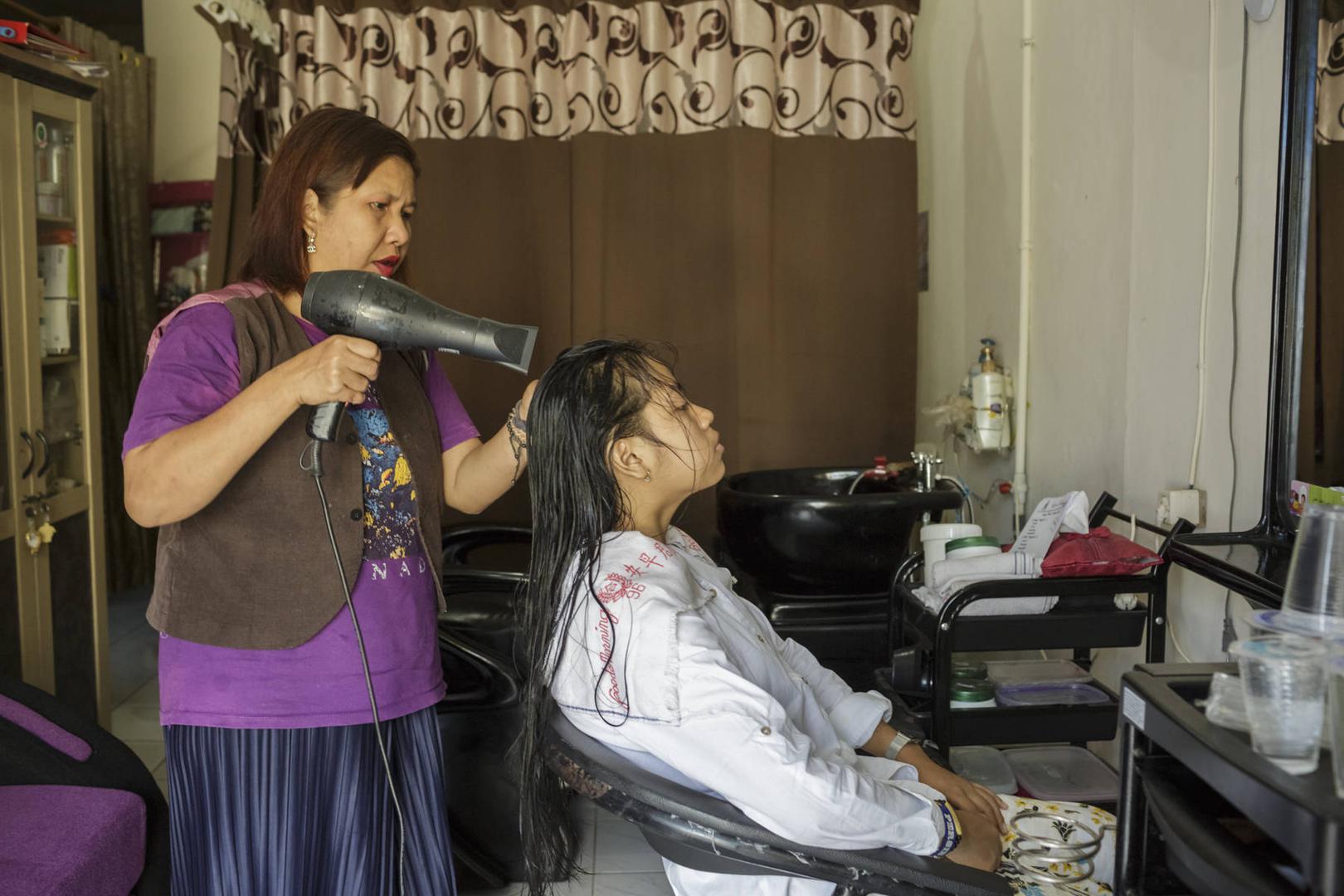 A woman with a psychosocial disability is working in her hair salon.