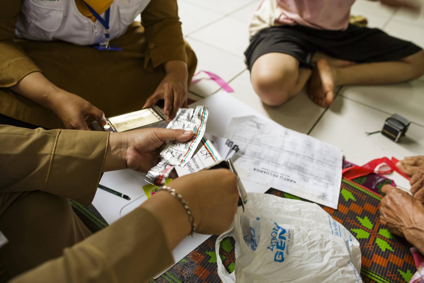Community health workers give medication to local residents in their home in Indonesia