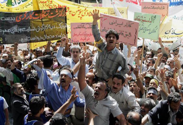 عمال إيرانيون ينشدون شعارات خلال مظاهرة عيد العمال أمام السفارة الأميركية السابقة في طهران في 1 مايو/أيار 2006 احتجاجاً على قرارات العمل والتأخير في سداد مستحقاتهم. @ 2006 Behrouz Mehri/AFP/Getty Images