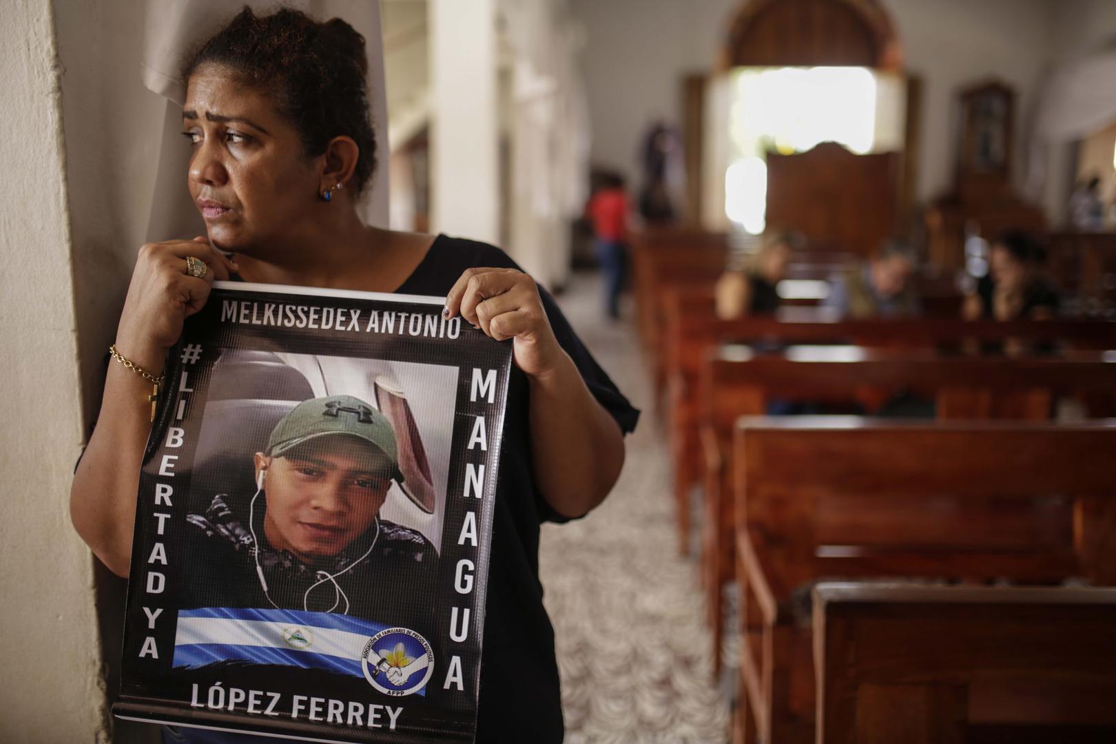 Martha Lorena Alvarado, mother of jailed anti-government demonstrator Melkissedex Antonio Lopez, holds a sign with an image of her son while participating in the hunger strike at the San Miguel Arcangel Church in Masaya, Nicaragua, on Thursday, November 1