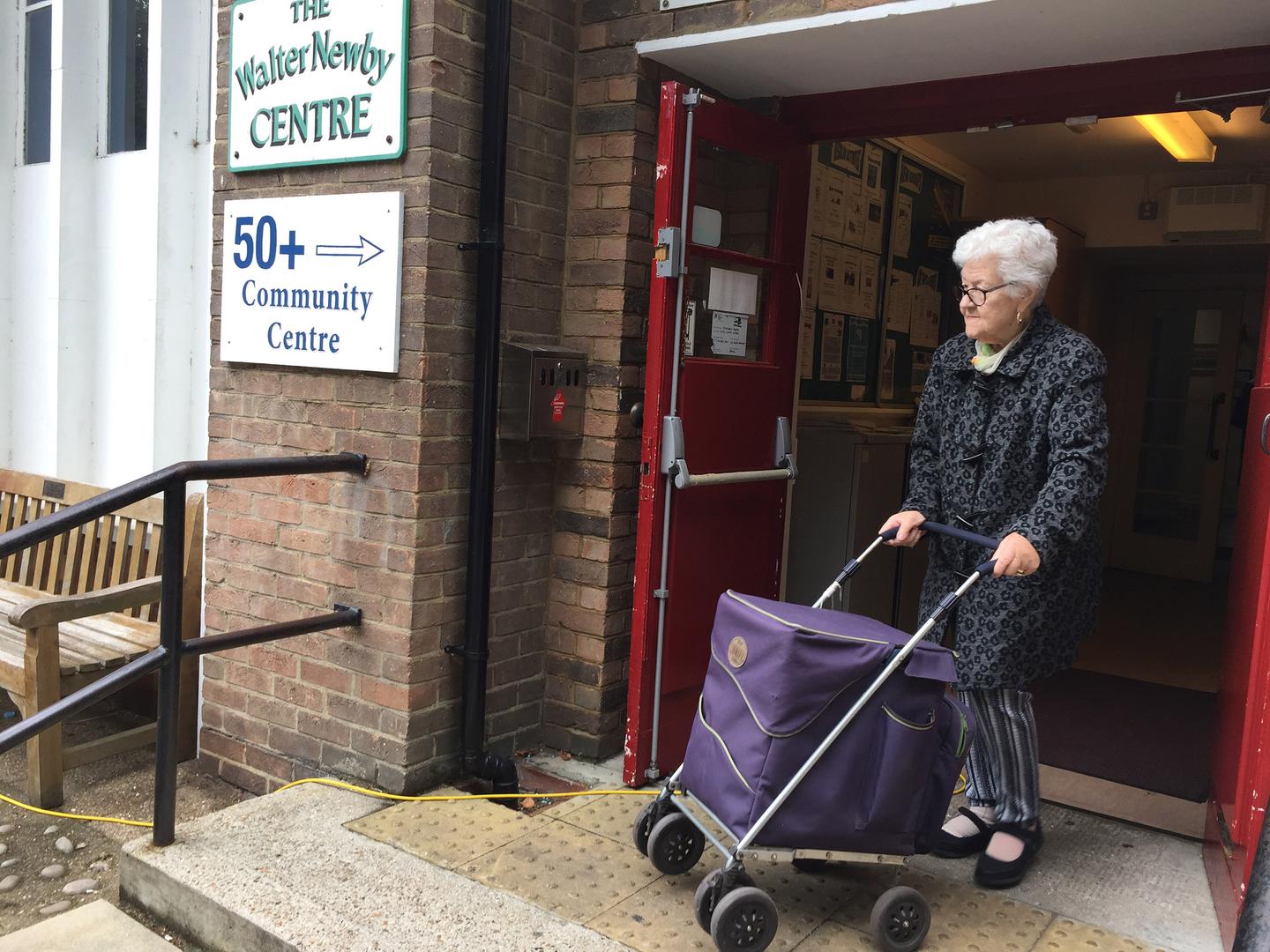 Older woman leaving a community center with programs for older people in East London. 