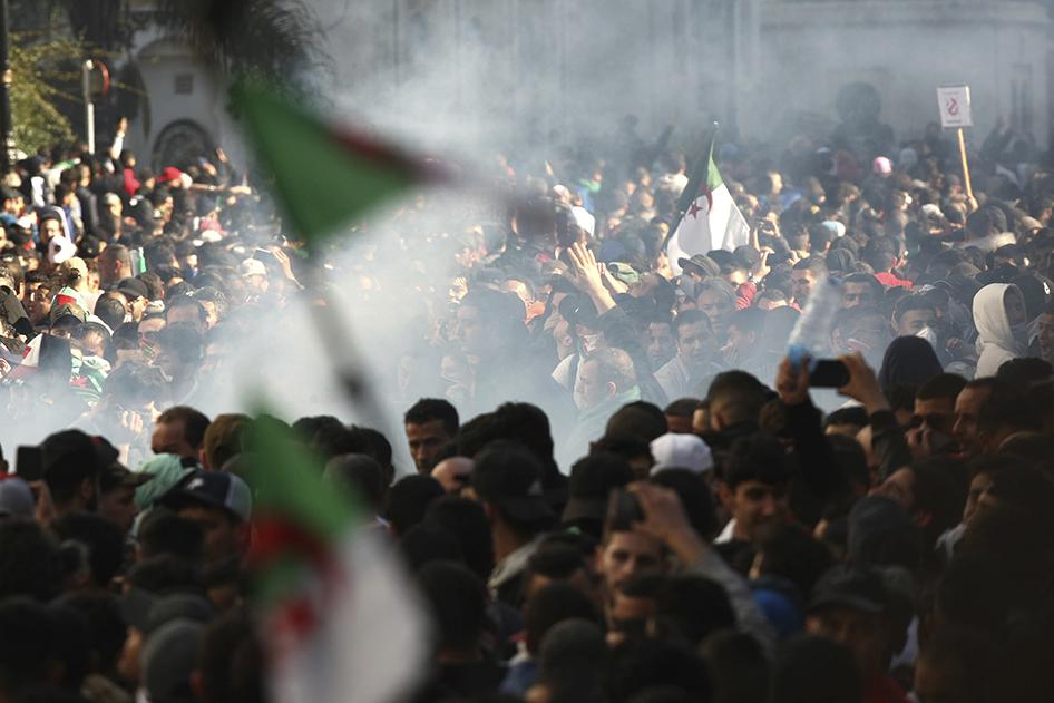 متظاهرون في مسيرة تندد بترشّح الرئيس عبد العزيز بوتفليقة لولاية خامسة، وسط سحابة من الغاز المسيل للدموع الذي أطلقته قوات مكافحة الشغب، 1 مارس/آذار 2019. 