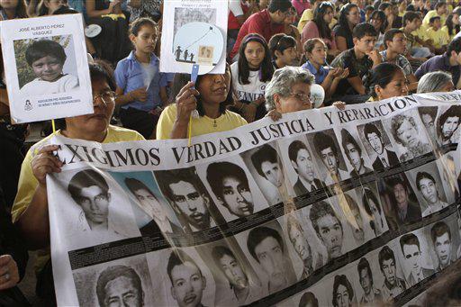 Mujeres llevan una pancarta con fotografías de personas desaparecidas, en una fecha dedicada a los niños y las niñas que desaparecieron durante el conflicto armado en el país, San Salvador, El Salvador, martes 29 de marzo de 2011