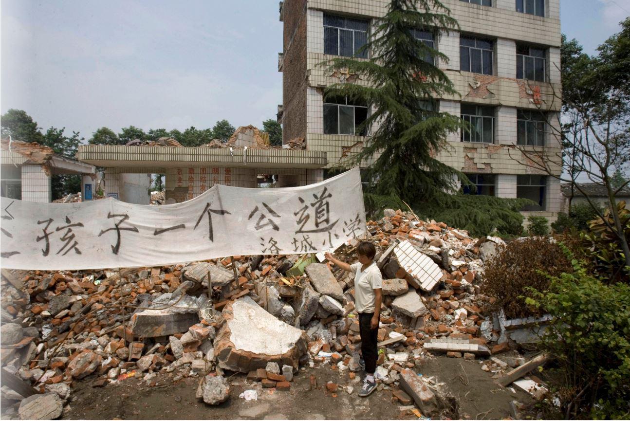 韦秦永（音）站在2008年5月12日四川震灾中倒塌的小学废墟前，她的12岁女儿杨乐（音）在这里失去生命，四川省洛水镇，2008年6月8日。