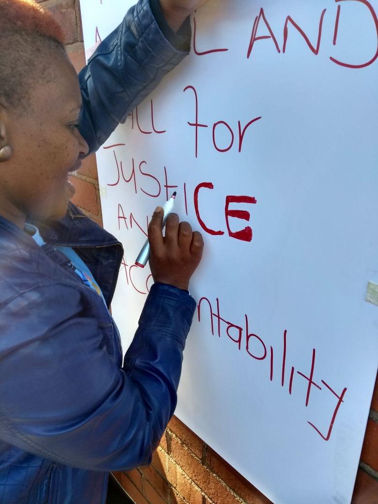 Phumzile Vilikhazi, who has an 18-year-old son with autism, writing “Today we appeal and call for justice and accountability” on a poster