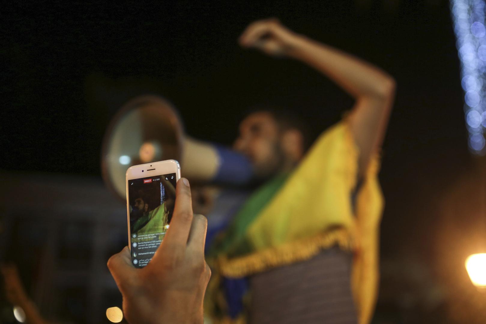 A citizen documenting a street protest with a smartphone in Morocco.