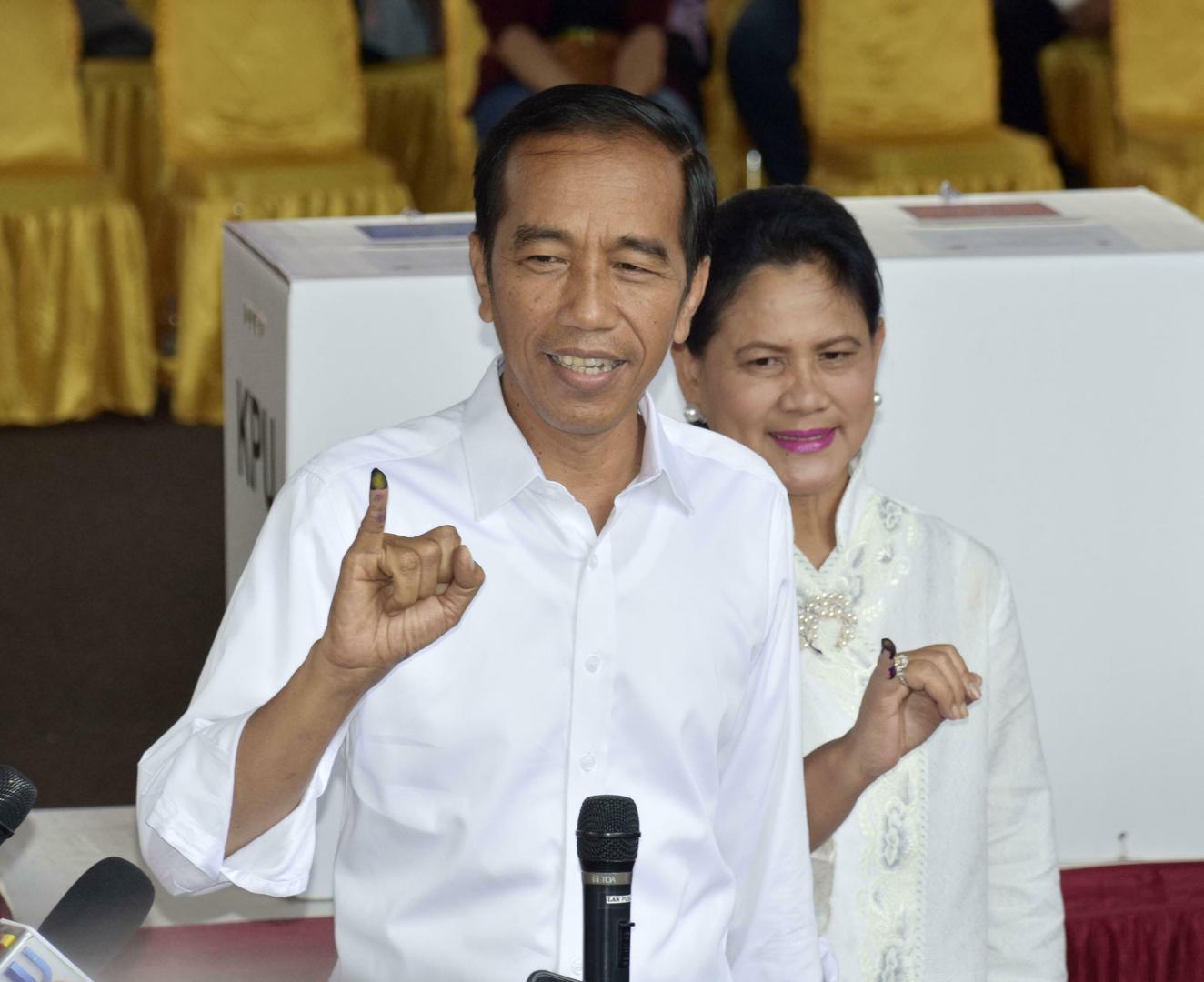 Indonesian President Joko "Jokowi" Widodo and his wife Iriana showing off their ink-marked fingers after casting ballots in the presidential election at a polling station in Jakarta on April 17, 2019. 