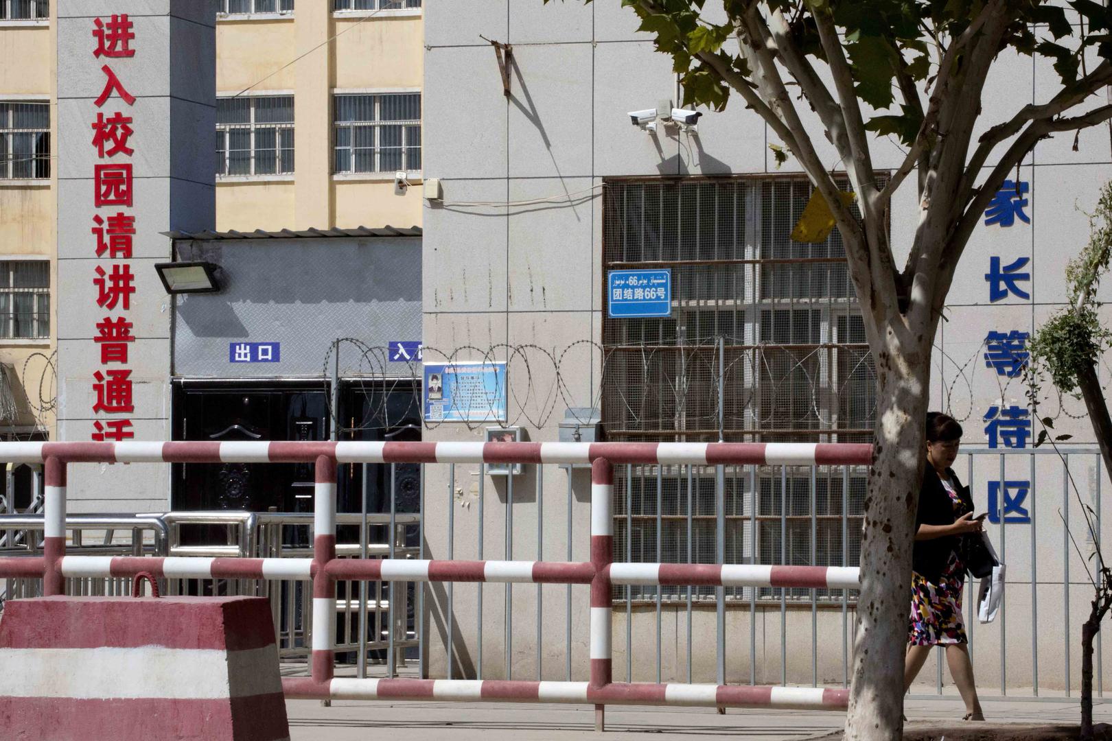 La façade d’un établissement scolaire à Peyzawat, dans la région du Xinjiang, en Chine. À gauche, en caractères rouges, figure l’inscription : « Entrée de l'école, veuillez parler le mandarin ». © 2018 AP Photo / Ng Han Guan