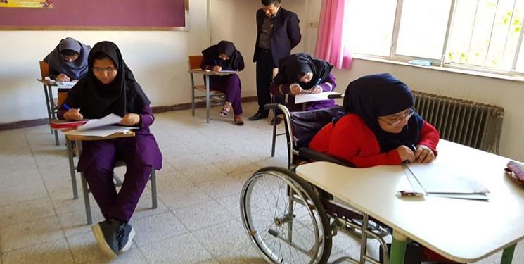 Estudante iraniano em uma cadeira de rodas com seus colegas de turma na sala de aula. © May 2019 Fars News Agency© May 2019 Fars News Agency