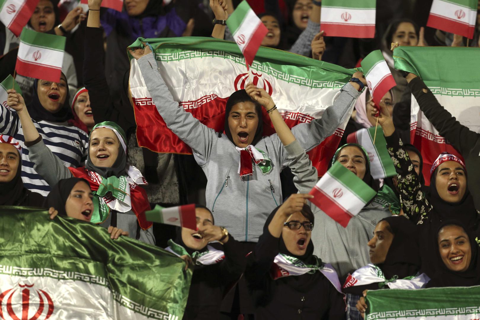 مشاهدات إيرانيات يهتفن بينما يلوّحن بعلم بلادهن خلال مباراة ودية لكرة القدم بين إيران وبوليفيا في ملعب أزادي (الحرية) في طهران، إيران، الثلاثاء في 16 أكتوبر/تشرين الأول 2018.