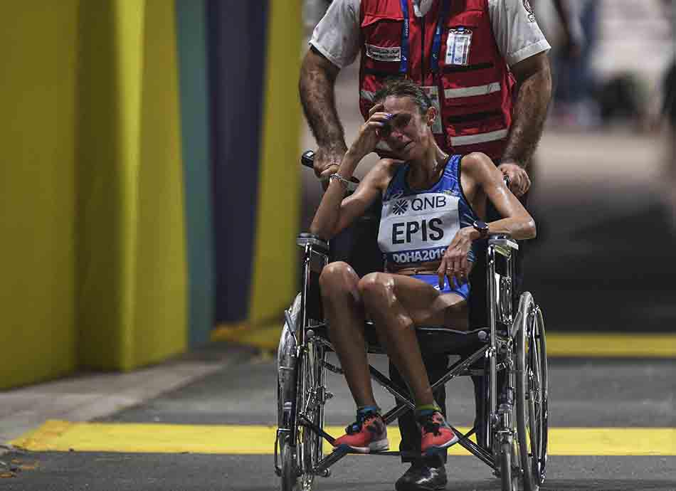 Italy's Giovanna Epis is pushed in a wheelchair during the women's marathon at the World Athletics Championships, in Doha, Qatar.