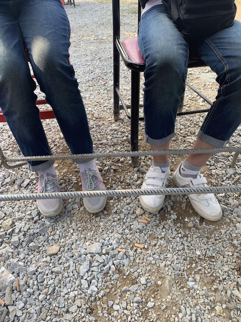 Two unaccompanied sisters, 16 and 17, sitting at a table outside Moria. Unaccompanied girls are housed in a “safe zone” that holds both unaccompanied boys under 14 and girls under 18, though they should be housed in separate, secure sections to mitigate t