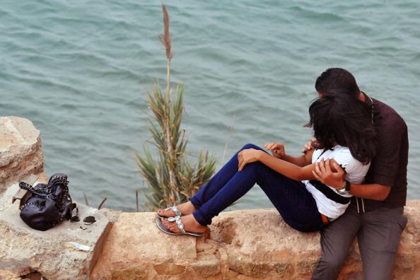 Un couple sur un muret surplombant l’océan à Rabat, Maroc. 