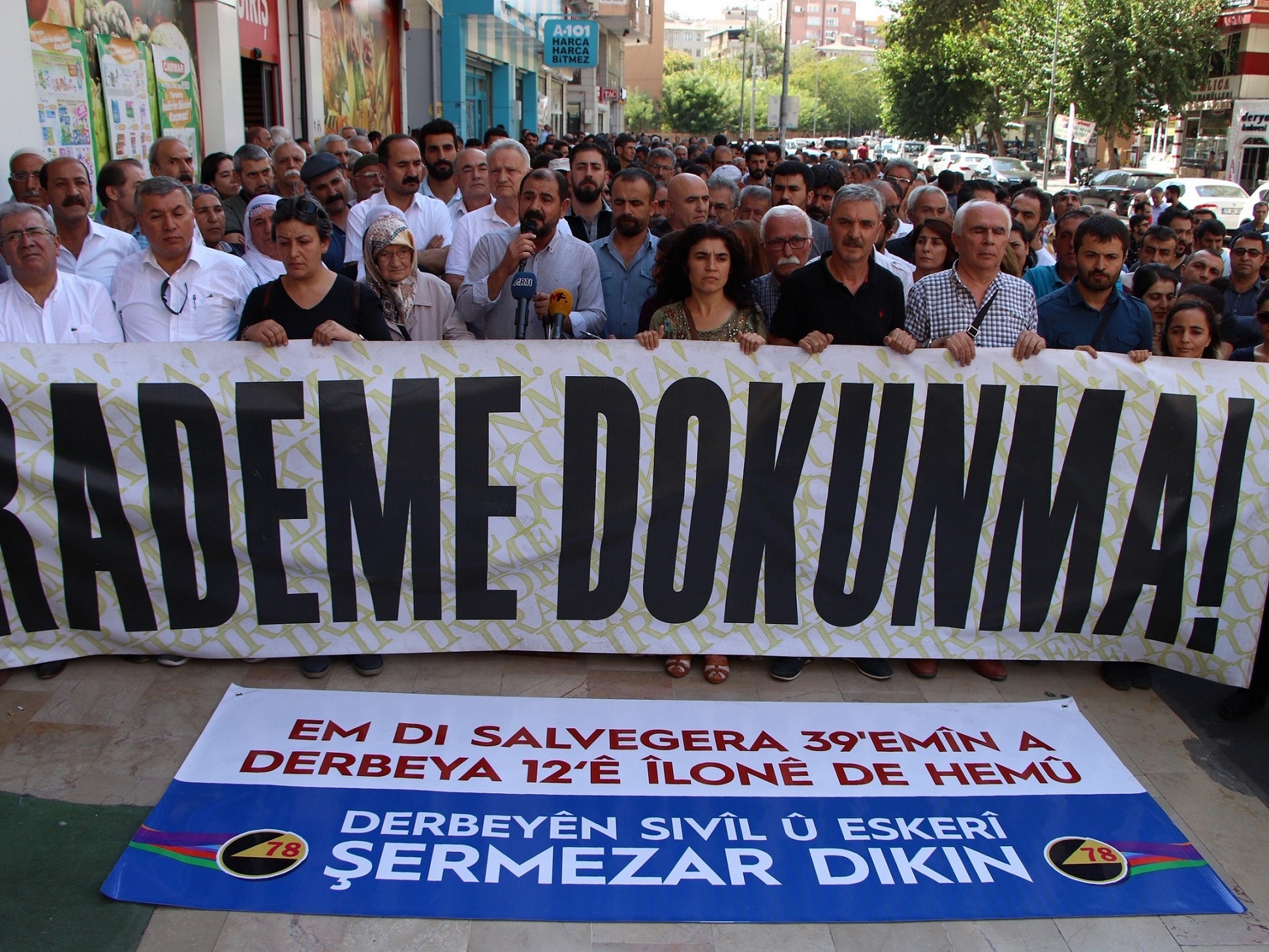 Diyarbakırlılar, seçilmiş belediye başkanlarının görevden alınmalarını protesto etmek için yaptıkları yürüyüşte pankart taşıyorlar