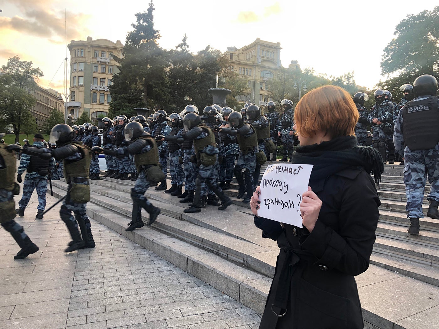 A protestor observes riot police during a peaceful protest in Central Moscow on August 10, 2019.