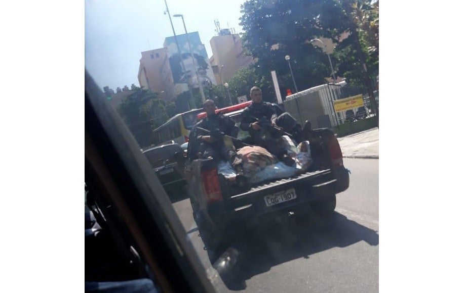 Policiais militares sentam-se com os pés em cima do que parece ser o corpo de uma ou mais vítimas mortas pela polícia no Rio de Janeiro, em 8 de fevereiro de 2019.