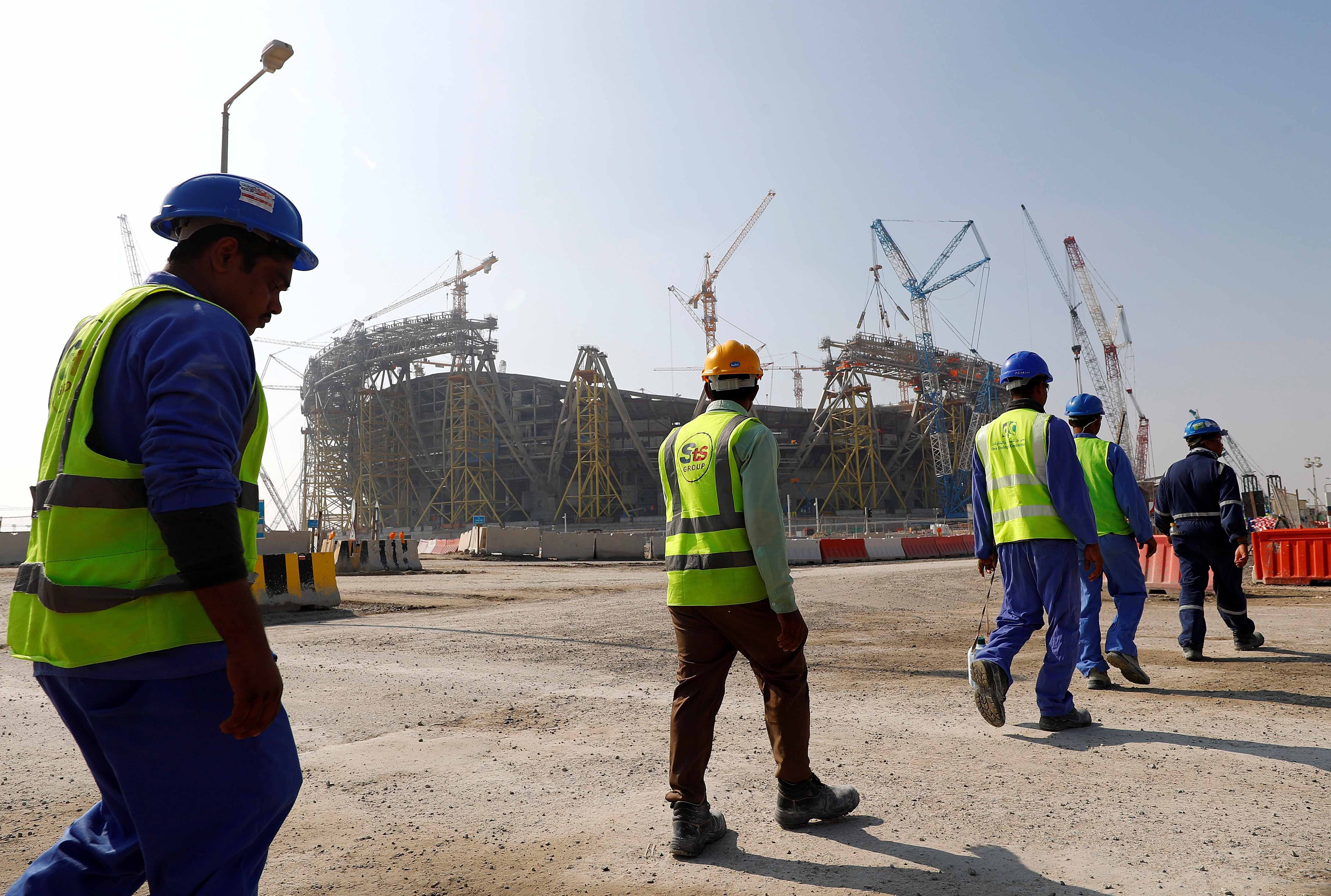 عمال يسيرون باتجاه ورشة ملعب لوسيل الذي سيُشيَّد لكأس العالم 2022 لكرة القدم، خلال جولة في الملعب في الدوحة، قطر، 20 ديسمبر/كانون الأول 2019. 
