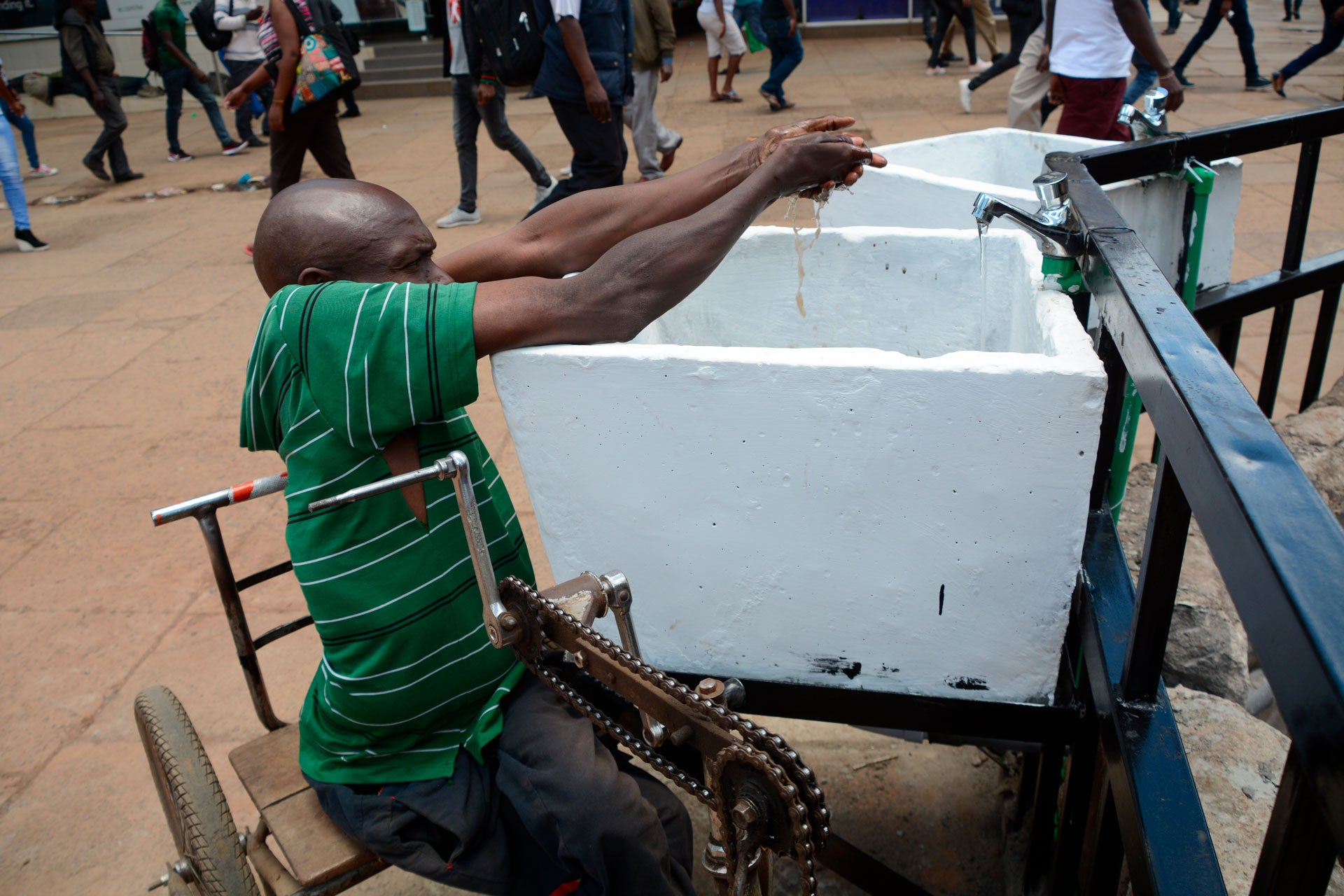 ​رجل في كرسي متحرك يغسل يديه في مغسلة عامة في نيروبي، كينيا، 22 مارس/آذار 2020، اتباعا للتعليمات الصحية من السلطات في إطار مكافحة انتشار فيروس "كورونا". إلا أن هذه الممارسة الأساسية صعبة أكثر عليه بسبب إعاقته. 
