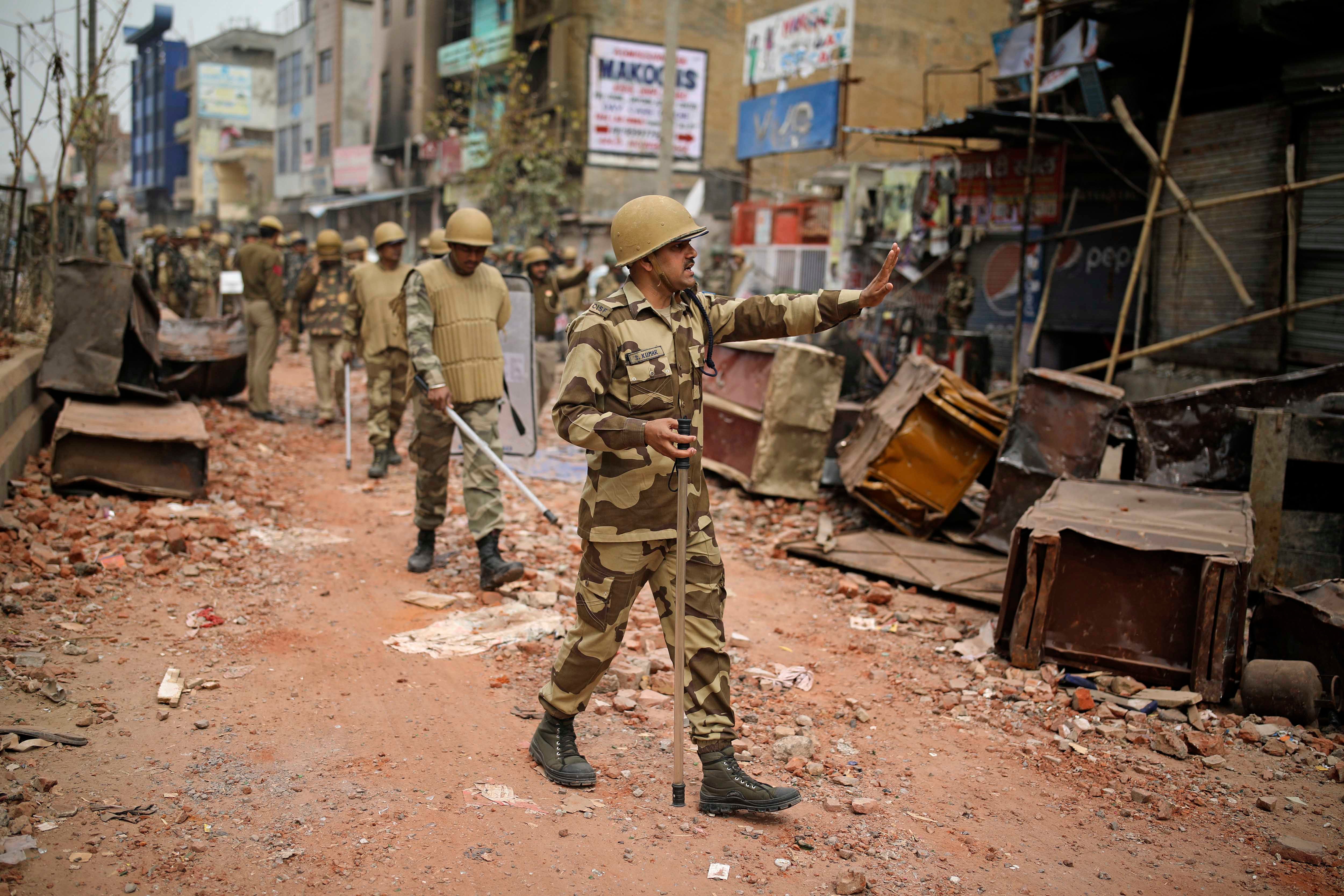 An Indian paramilitary soldier asks residents to stay indoors as they patrol a street vandalized in February 25th's violence in New Delhi, India, February 27, 2020.