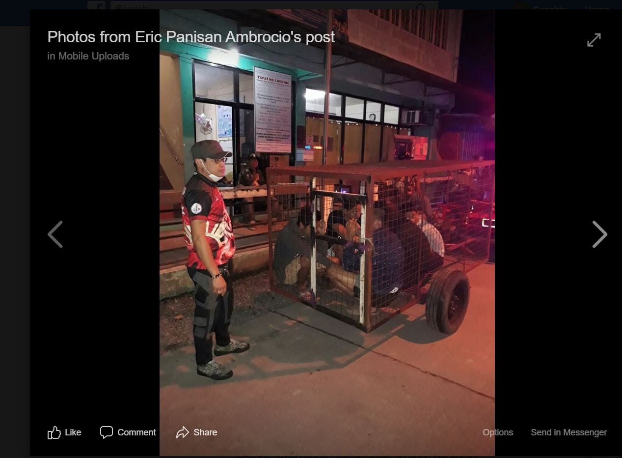 A screenshot of an officer with five youths locked inside a dog cage after breaking curfew in Laguna province, the Philippines on March 20, 2020. © 2020 Facebook