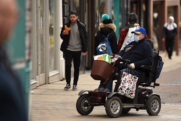 A man wears a protective face mask as he drives a mobility scooter in central Leeds on the morning of March 21, 2020.