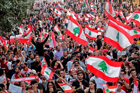 Lebanese protesters wave national flags during demonstrations to demand better living conditions on October 21, 2019 in downtown Beirut.