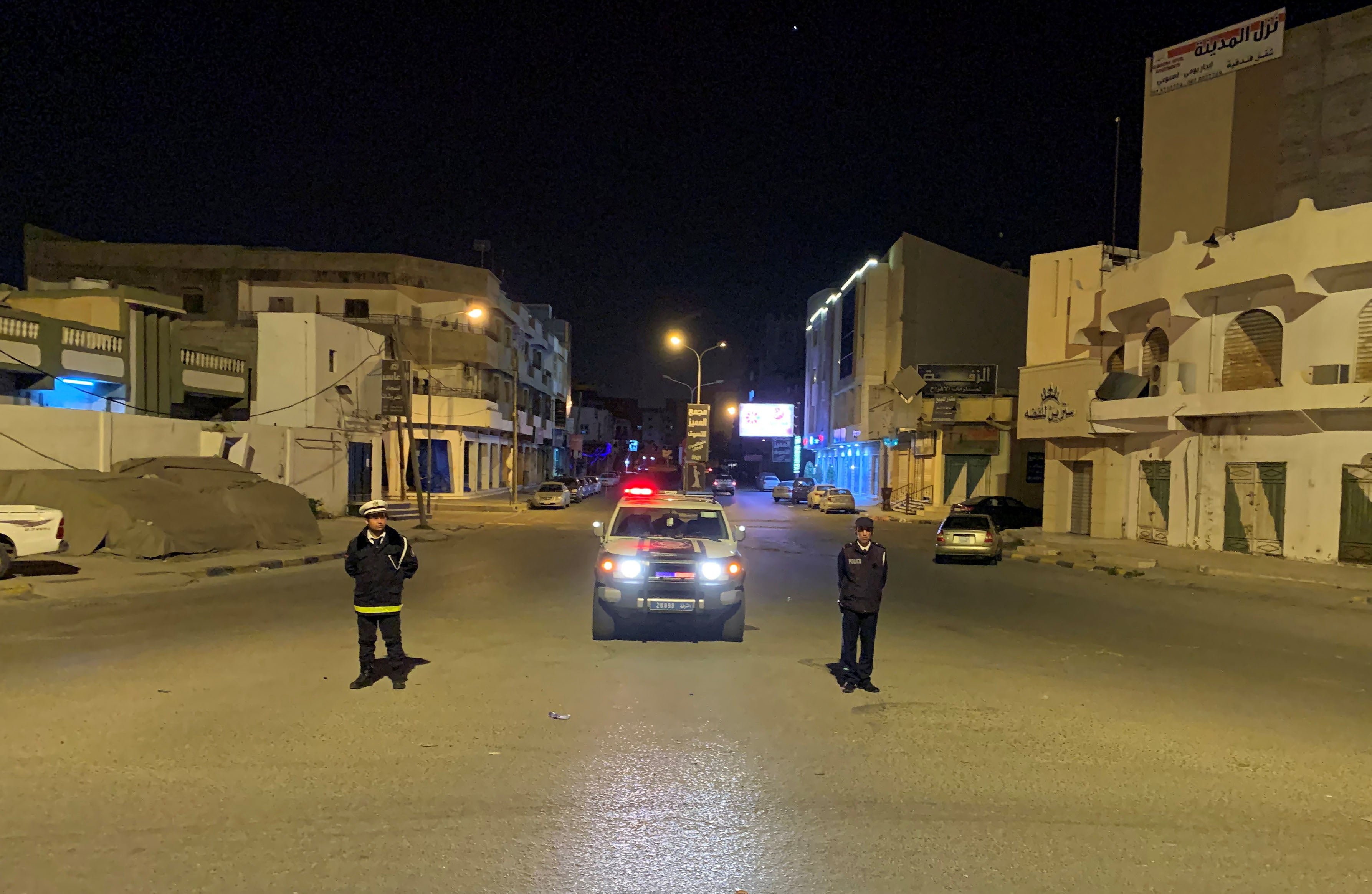 شرطيان يقفان وسط الطريق خلال حظر تجوّل فُرِض ضمن التدابير الاحترازية لمواجهة فيروس كورونا المستجد، في مصراتة، ليبيا في 22 مارس/آذار 2020. 