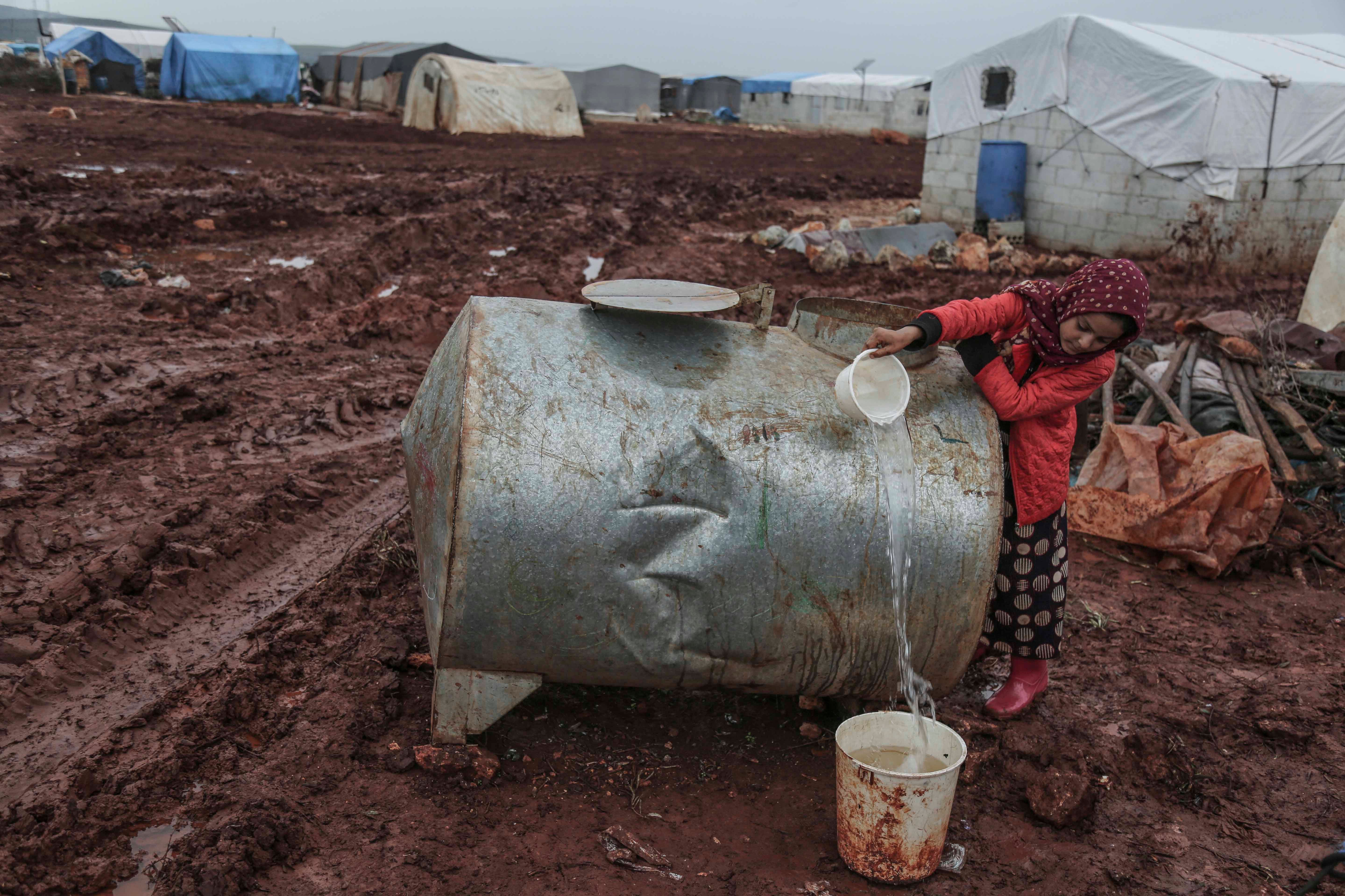 Une jeune fille syrienne recueille de l'eau conservée dans une citerne, dans un camp pour personnes déplacées qui se situe dans le nord de la Syrie, près de la frontière avec la Turquie. 