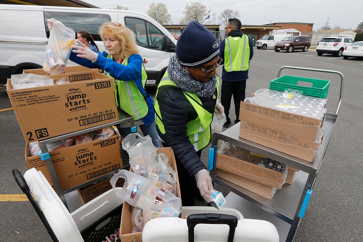 School workers load food packs as they distribute meals to students at Fairfield Middle School in Richmond, Virginia, March 18, 2020.