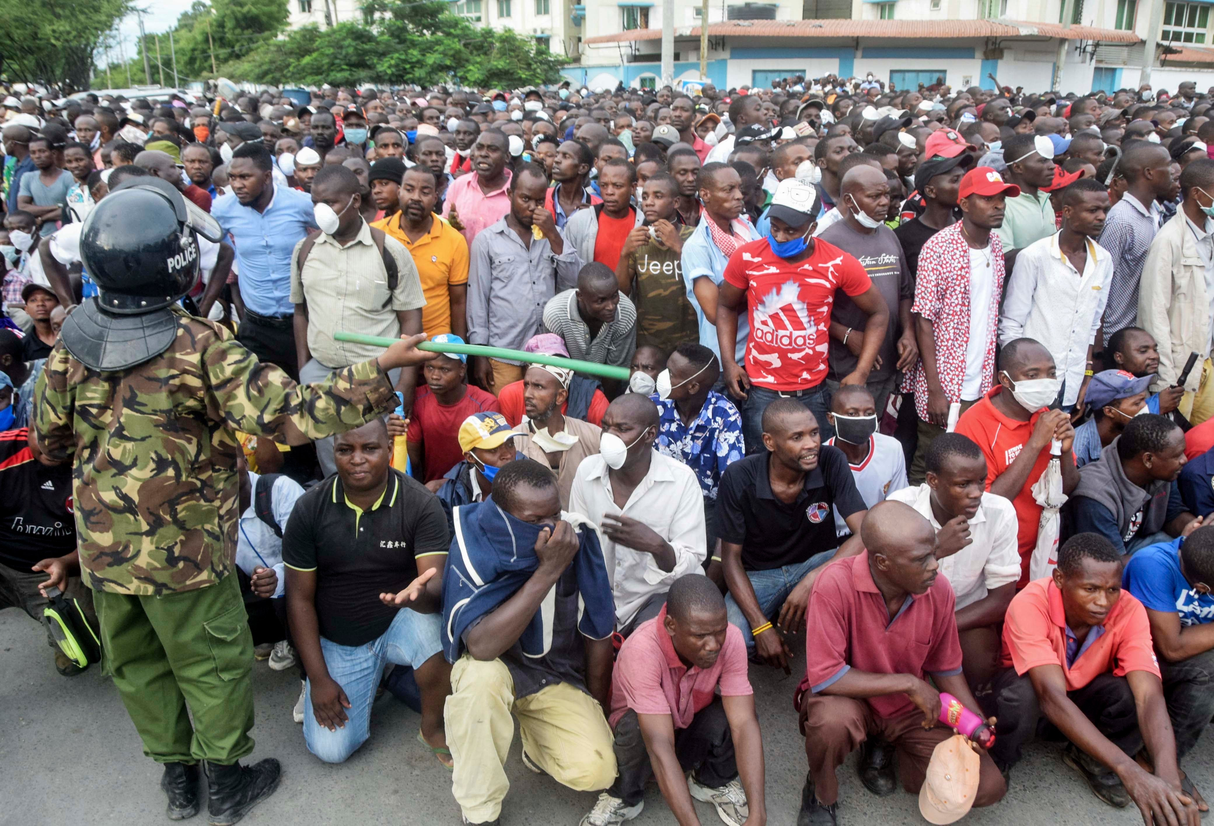 Kenyan police hold back ferry passengers causing a crowd to form outside the ferry in Mombasa, Kenya on Friday, March 27, 2020. 