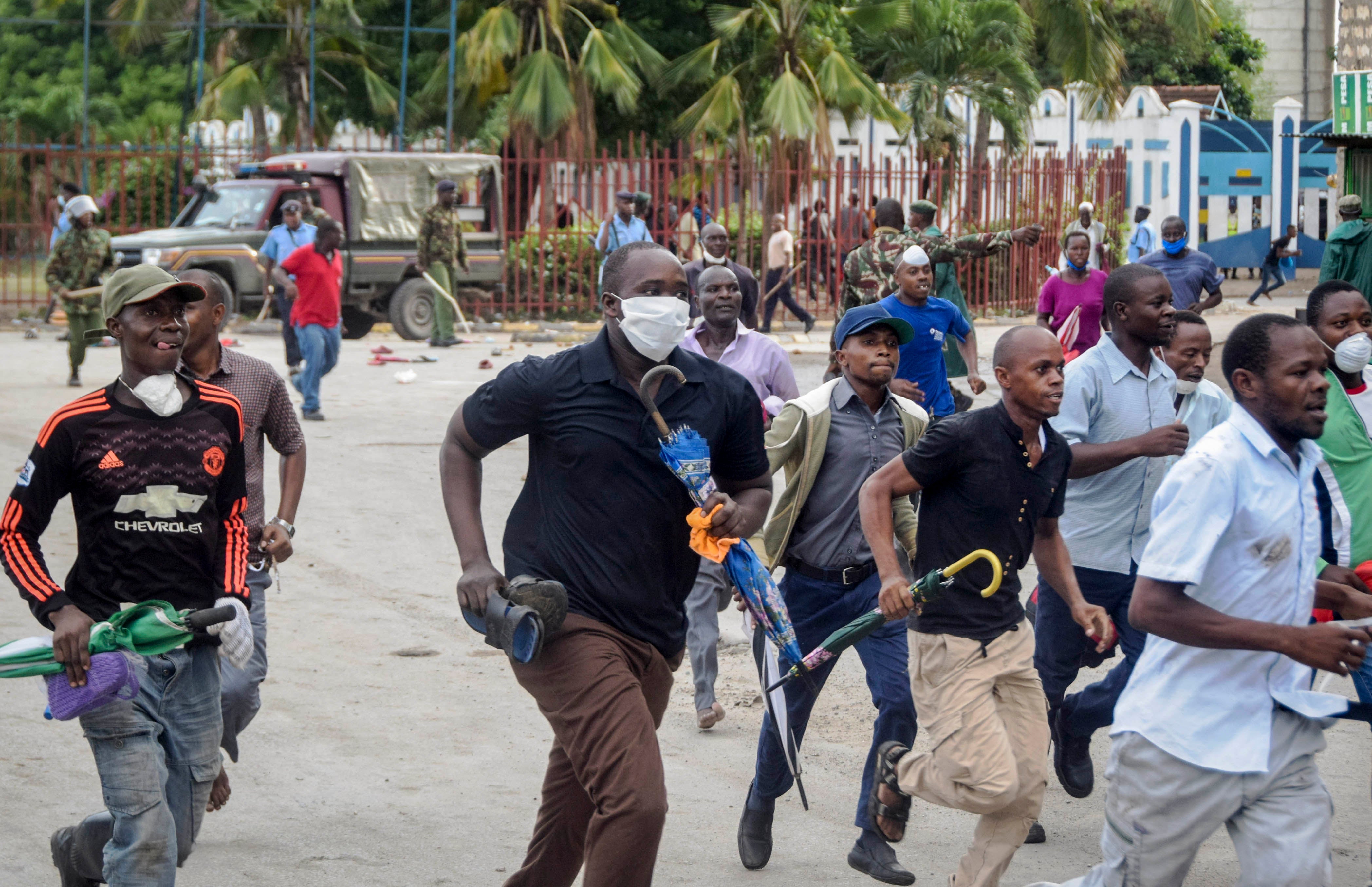Ferry passengers flee from police firing tear gas, after new measures aimed at halting the spread of the new coronavirus instead caused a crowd to form outside the ferry in Mombasa, Kenya Friday, March 27, 2020. 