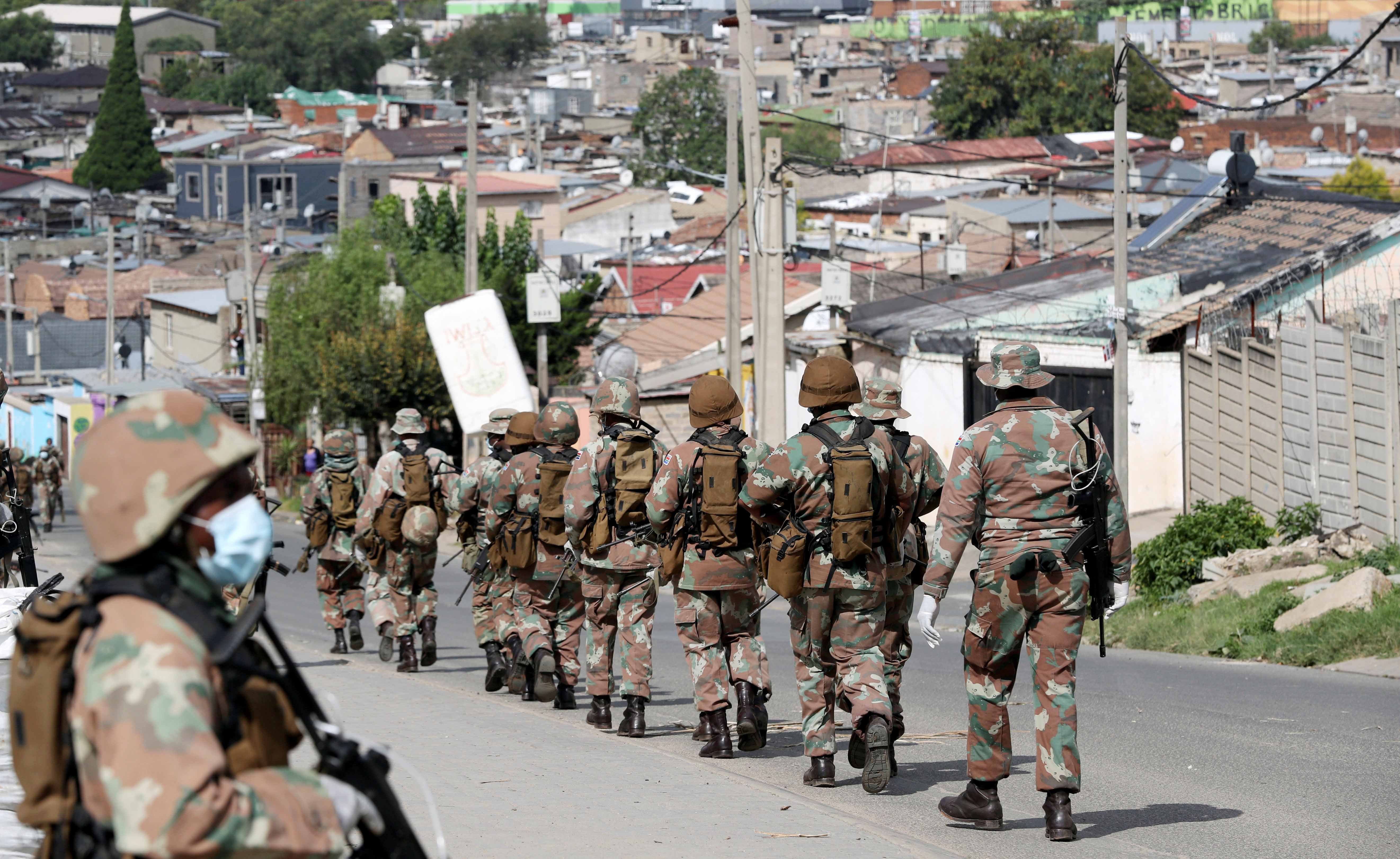 Des soldats patrouillent dans une rue du township d’Alexandra, dans la banlieue de Johannesburg, le 28 mars 2020, afin de contrôler la mise en œuvre des mesures de confinement prises pour endiguer la propagation de la pandémie de COVID-19 en Afrique du Su