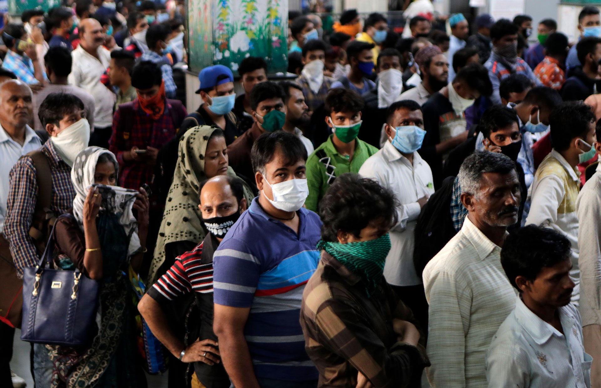 Indians, some wearing protective masks as a precaution against COVID-19, wait to buy train tickets at Chhatrapati Shivaji Terminus in Mumbai, India, March 20, 2020.