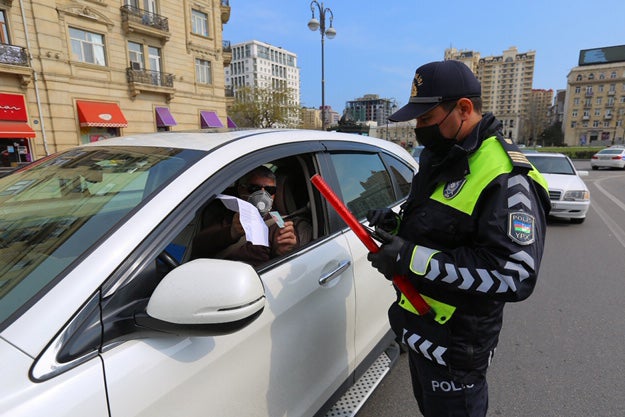A policeman verifies a driver's permission to be moving around the city in April 2020. 