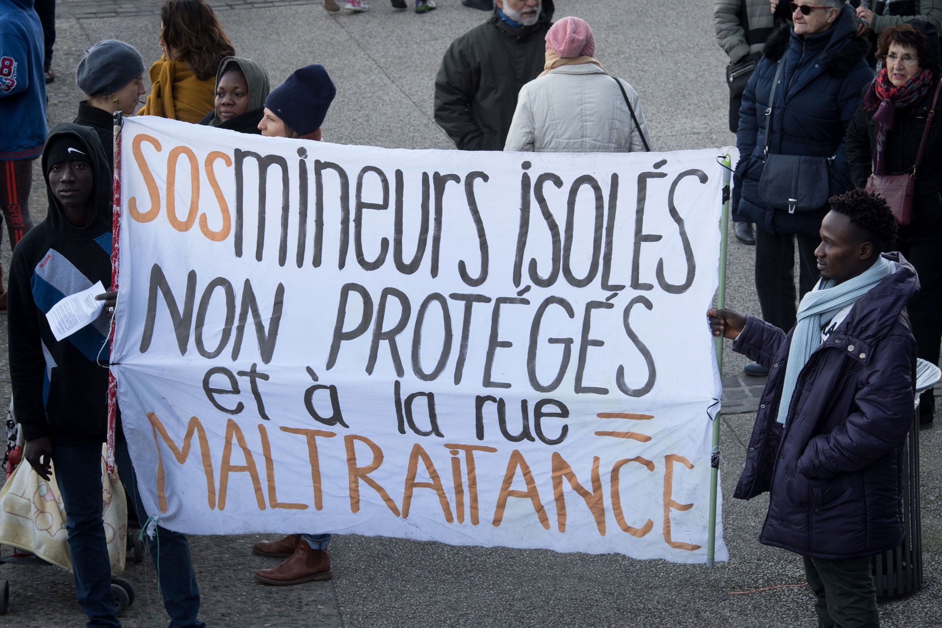 Migrants hold a banner reading "SOS isolated minors unprotected and on the street = abuse" as they demonstrate against the living conditions of unaccompanied migrant minors and the lack of accommodation, outside the departmental council building in Marsei