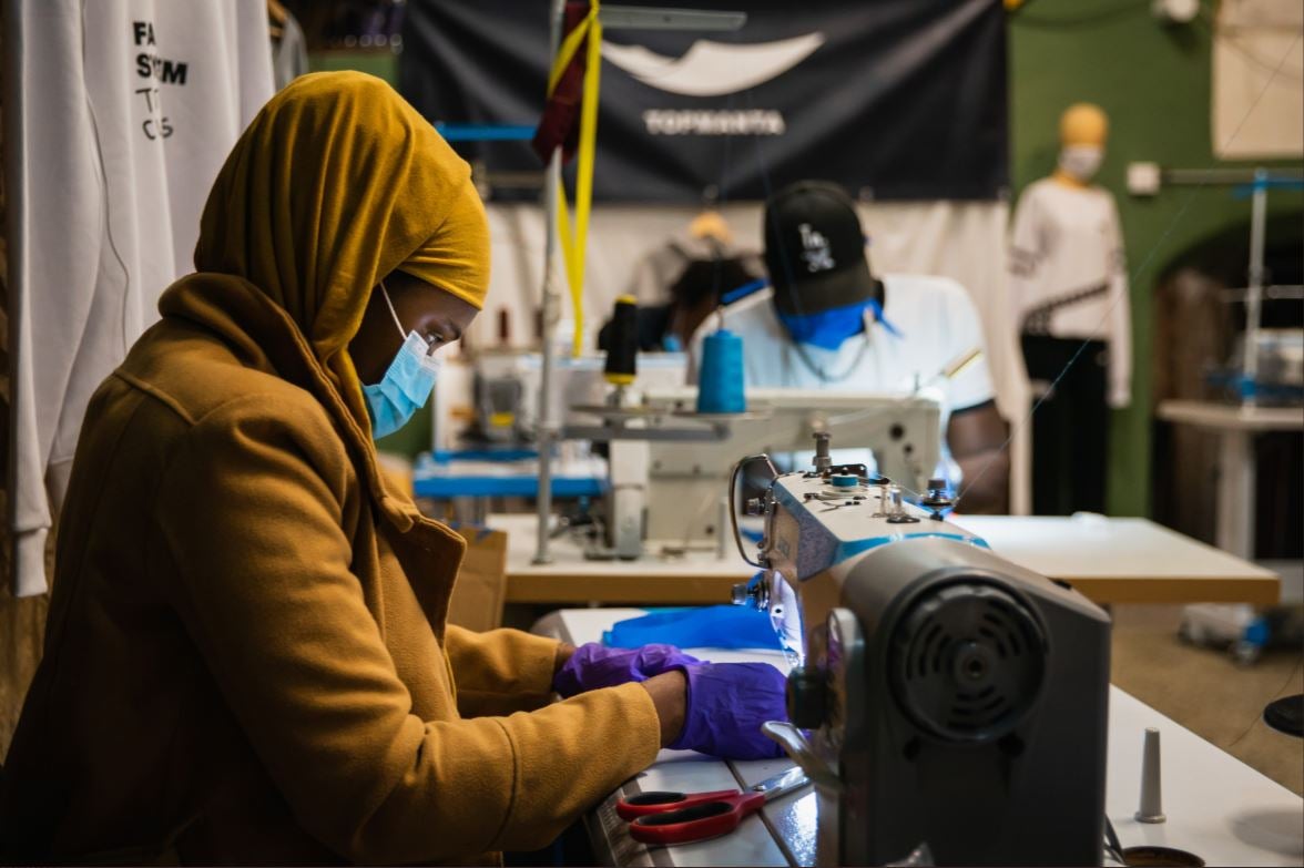 A woman from Barcelona’s street vendors union sews protective face masks for the use of health care workers whose supplies are running low, March 2020