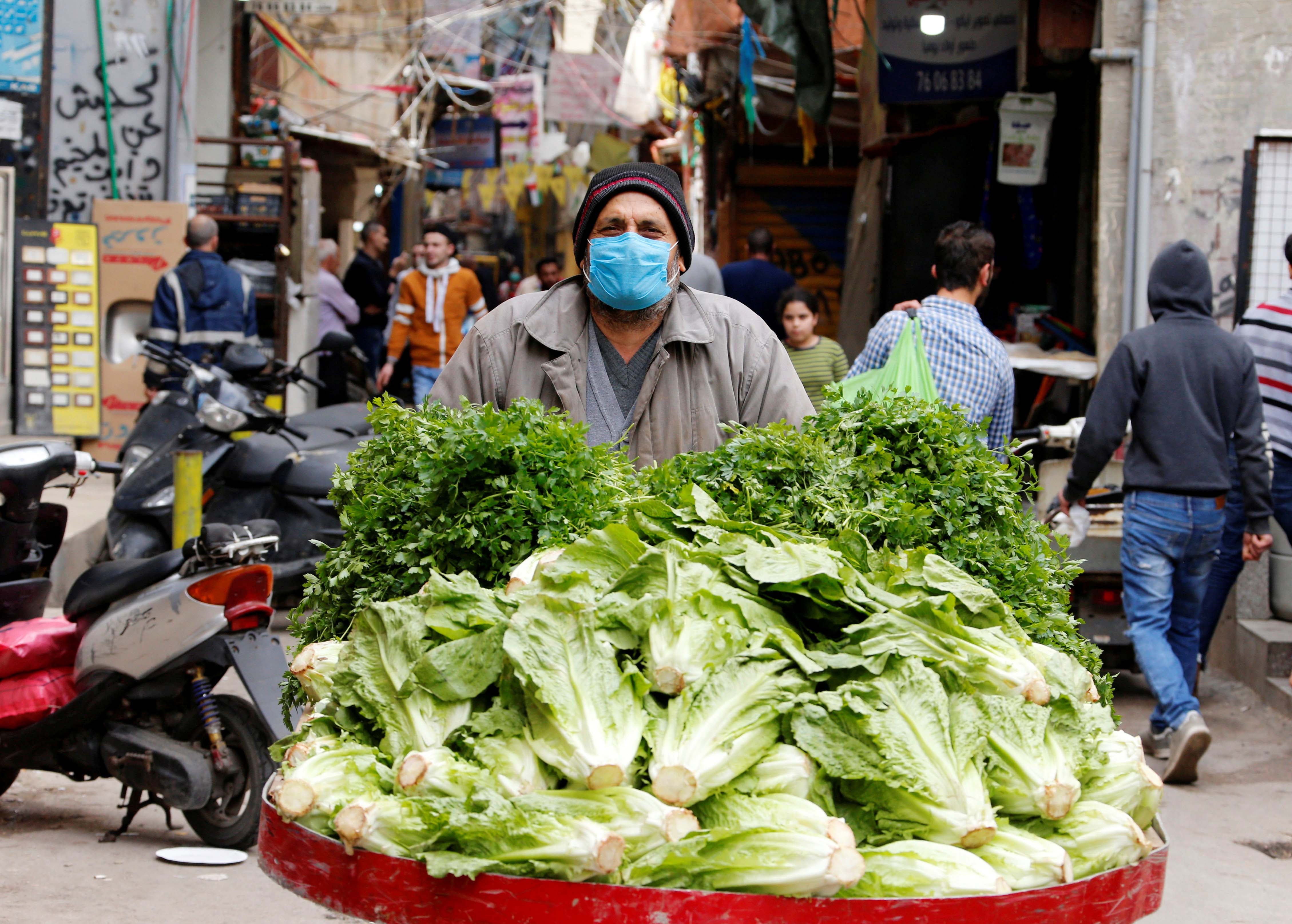 A street vendor pushes his cart in Shatila Palestinian refugee camp, wearing a face mask to try to protect against the spread of COVID-19, in Beirut suburbs, Lebanon, March 30, 2020.