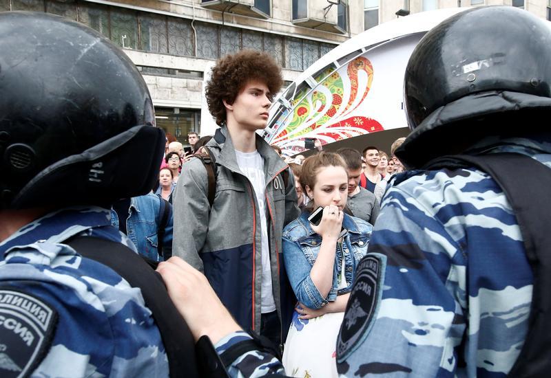A couple stands behind riot police during an anti-corruption protest organised by opposition leader Alexei Navalny, on Tverskaya Street in central Moscow, Russia, June 12, 2017.