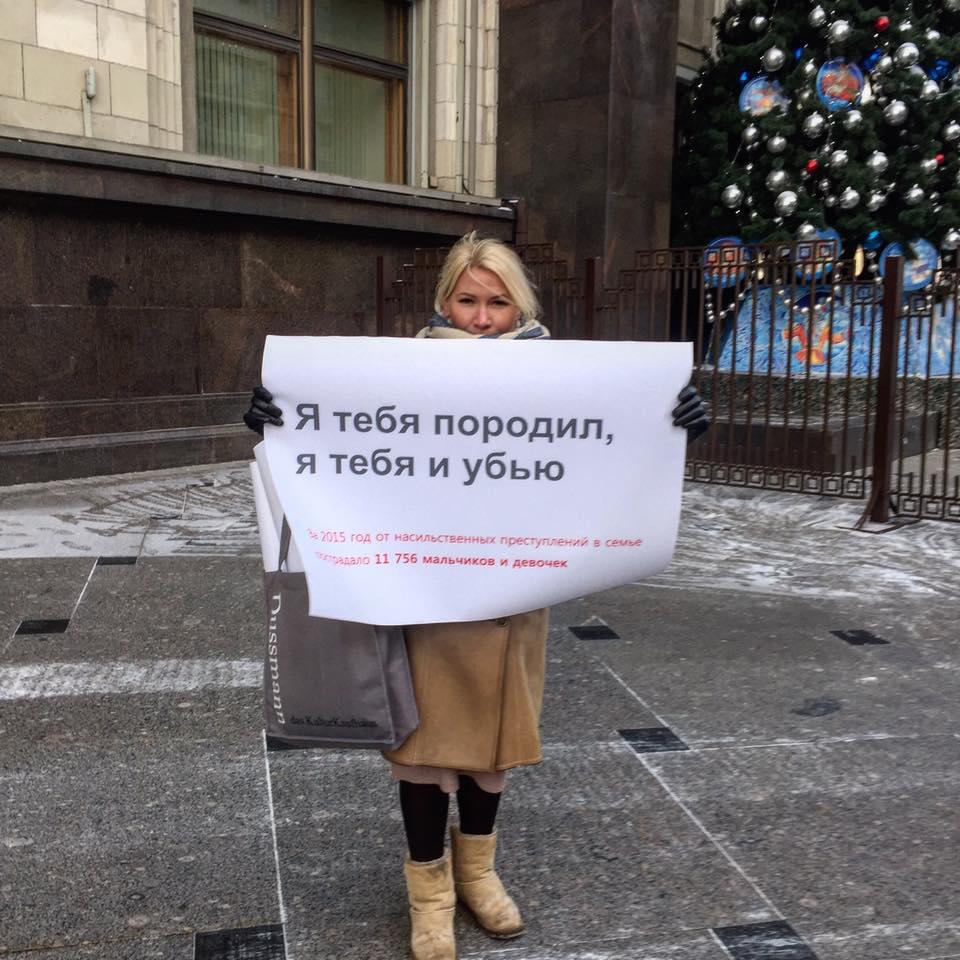 Russian woman protesting decriminalization of domestic violence in front of Russia’s state parliament building holds up a sign: “’I gave you life, and it is mine to take.’ 11 756 boys and girls subjected to domestic violence in 2015.” Moscow, Russia, Janu