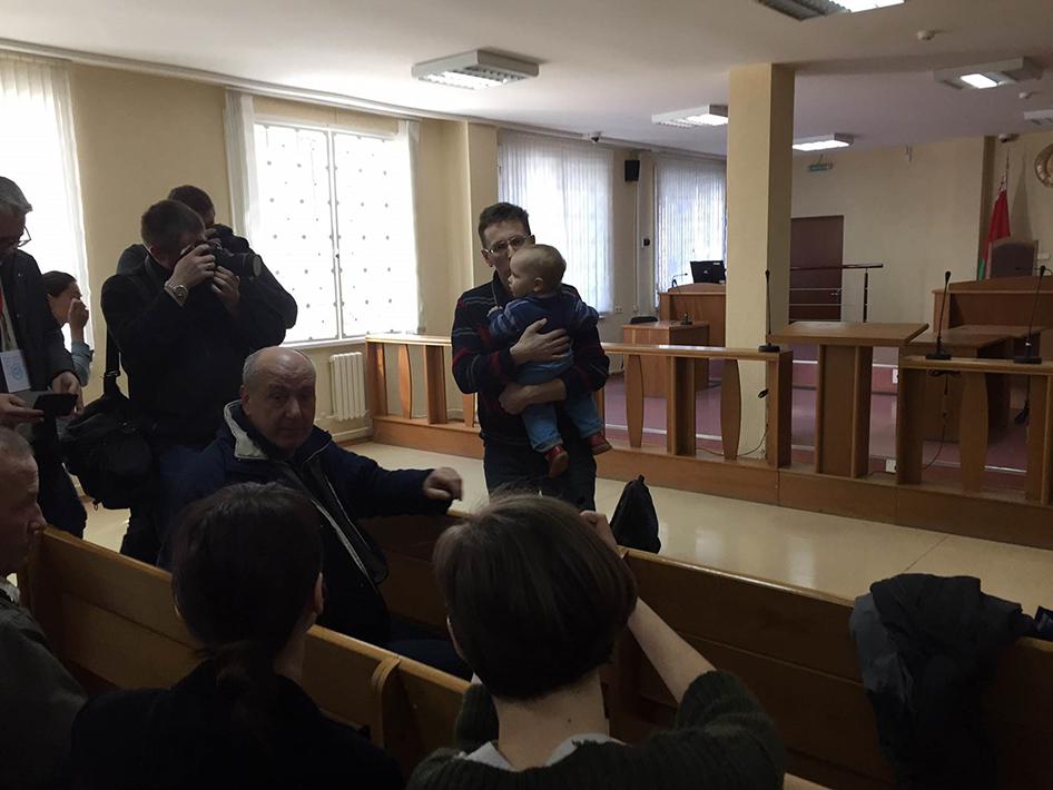 Алесь Логвинец держит на руках своего сына перед началом слушания в зале суда 27 марта 2017 года.