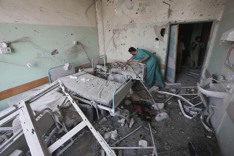 مسعف فلسطيني يعاين غرفة متضررة في مستشفى شهداء الأقصى في دير البلح، وسط قطاع غزة، بعد أن قُصف المبنى من الجيش الإسرائيلي في 21 يوليو/تموز 2014، ما قتل 3 أشخاص على الأقل وجرح 40 آخرين.