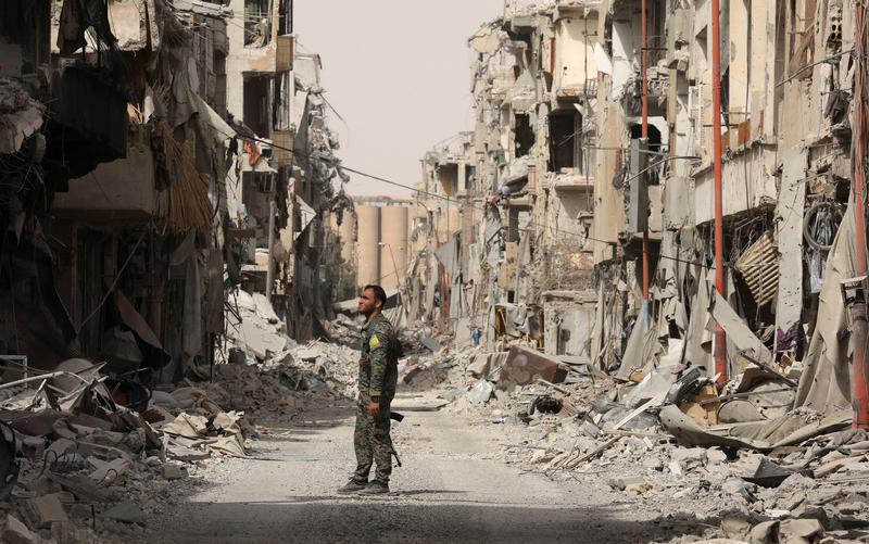 A fighter from Syrian Democratic Forces (SDF) stands next to debris of damaged buildings in Raqqa, Syria, September 25, 2017.
